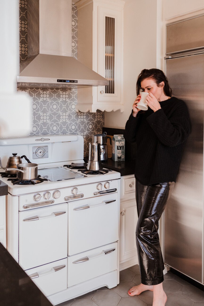 Mulher tomando café na cozinha.