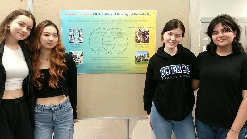 Quatro estudantes compartilhando seu pôster sobre ciência ocidental vs. Ecologia Tradicional