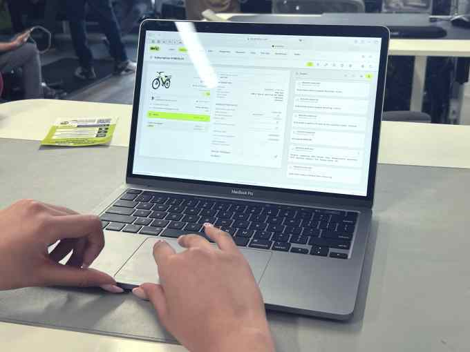 Mãos em um laptop Apple aberto exibindo o software de gerenciamento do Whizz.