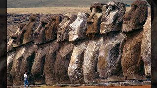 Uma mulher olha para uma fileira de enormes estátuas de pedra.