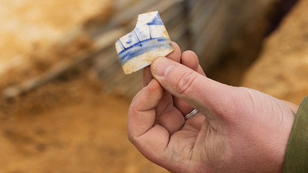 Uma pessoa segura um caco de cerâmica branca e azul.