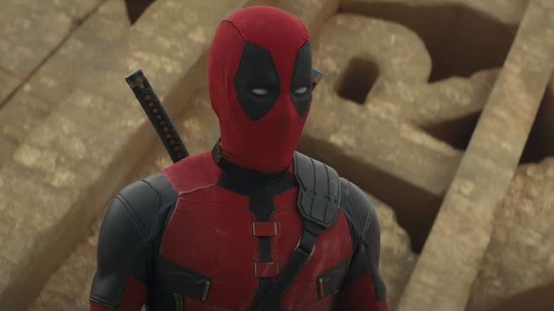 Deadpool em pé na frente do logotipo da Fox desintegrado em Deadpool e Wolverine