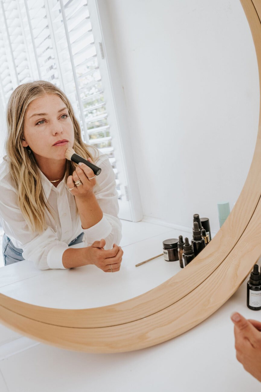 Woman doing makeup in mirror.