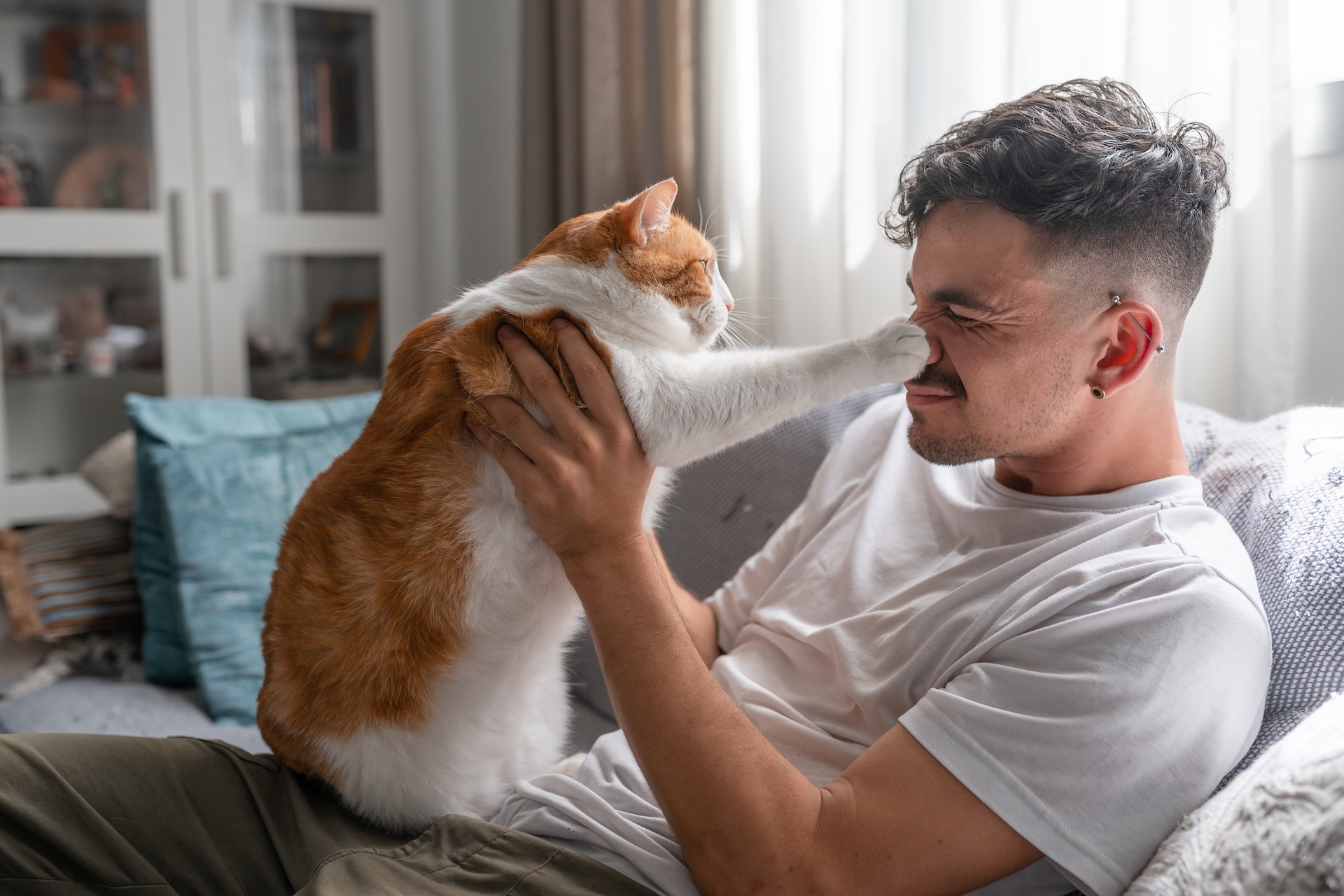 Um homem brinca com seu gato laranja