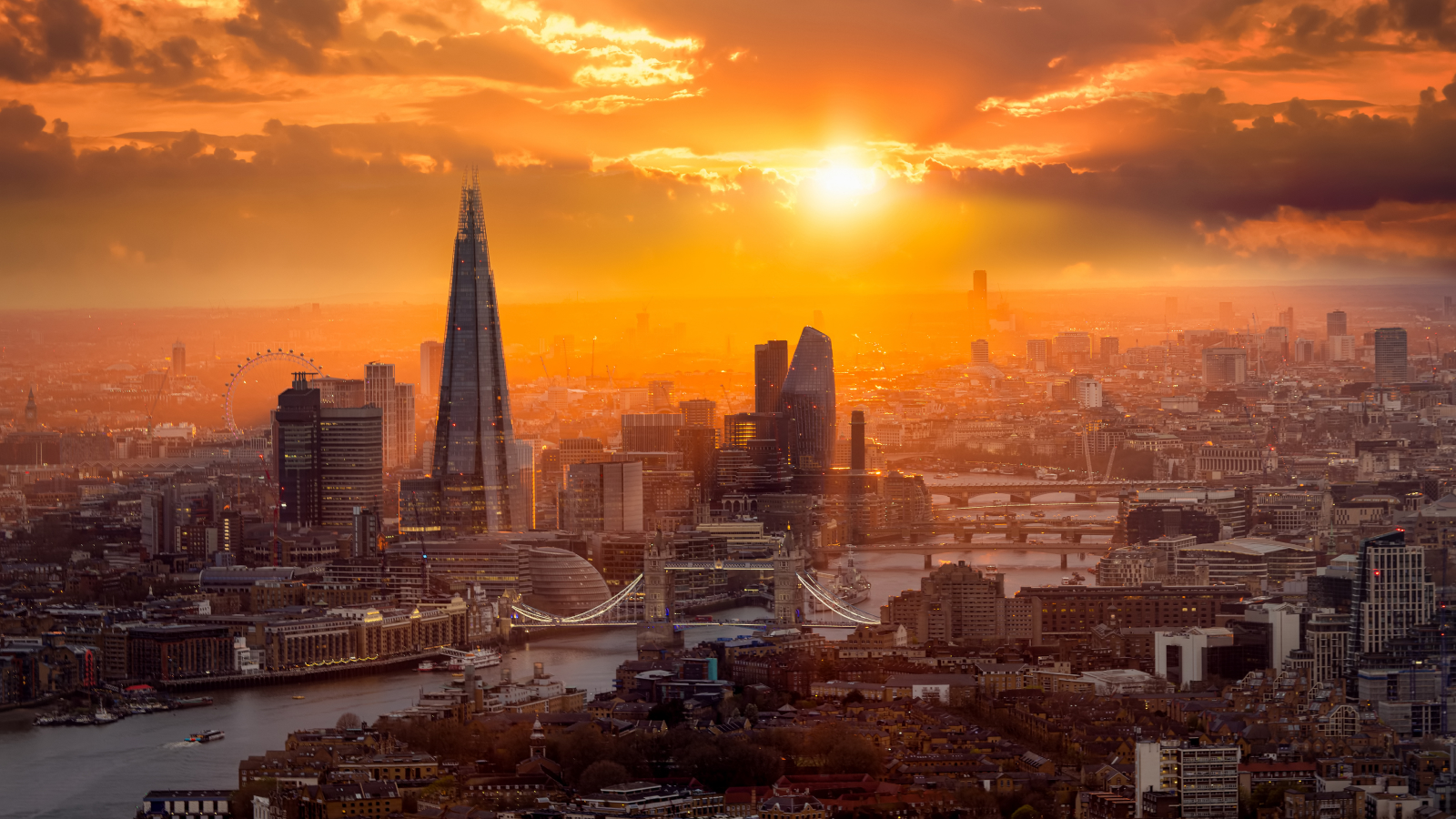 Um lindo pôr do sol atrás do horizonte de Londres com a Tower Bridge, o Rio Tâmisa e os arranha-céus corporativos.