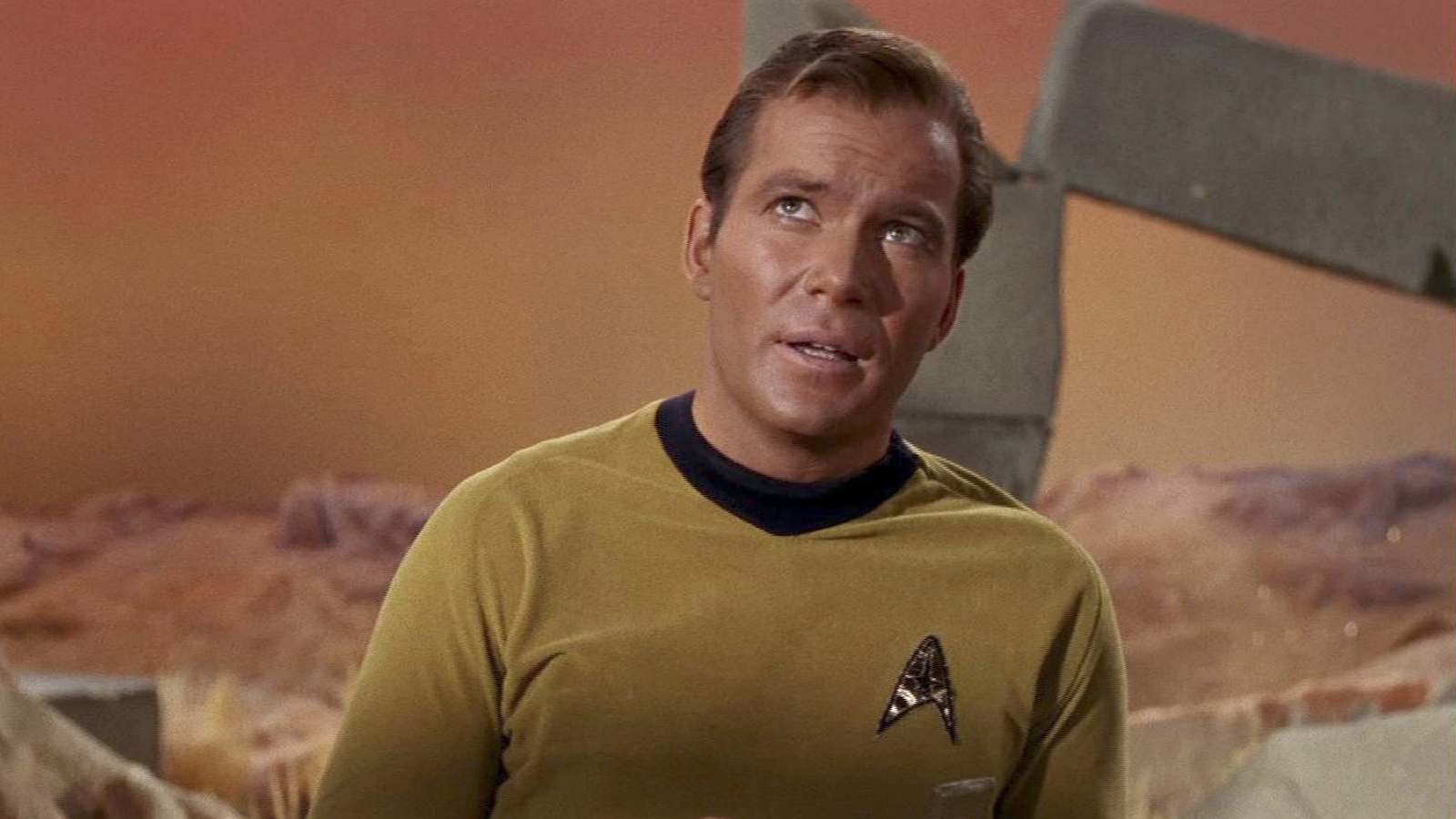 Uma captura de tela de um episódio de Star Trek mostrando William Shatner como Capitão James T. Kirk usando o icônico distintivo da Frota Estelar