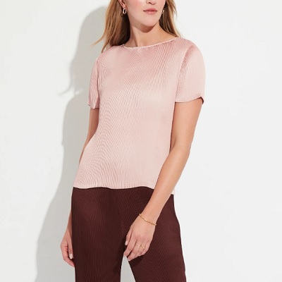 Uma mulher vestindo uma blusa rosa claro e calças marrons