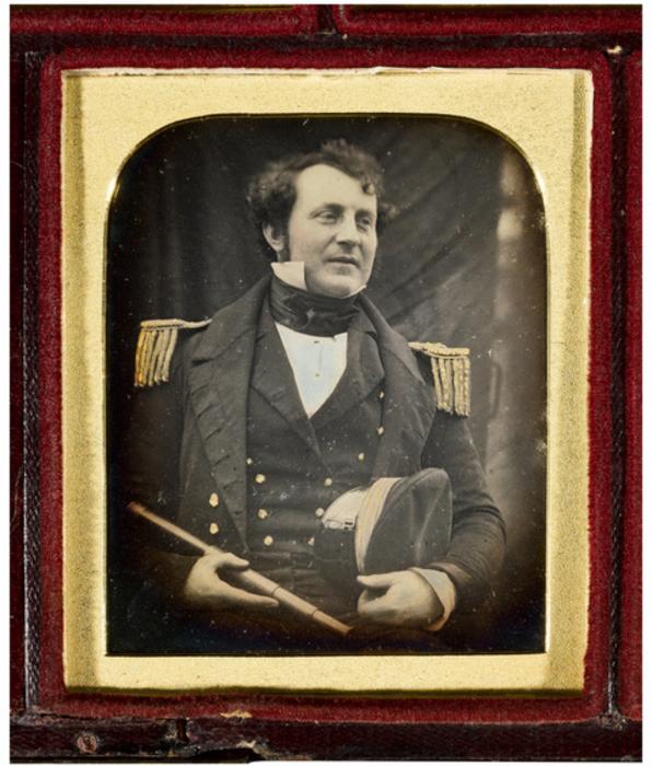 Uma foto em preto e branco em uma moldura. Mostra James Fitzjames em um uniforme da Marinha Real.